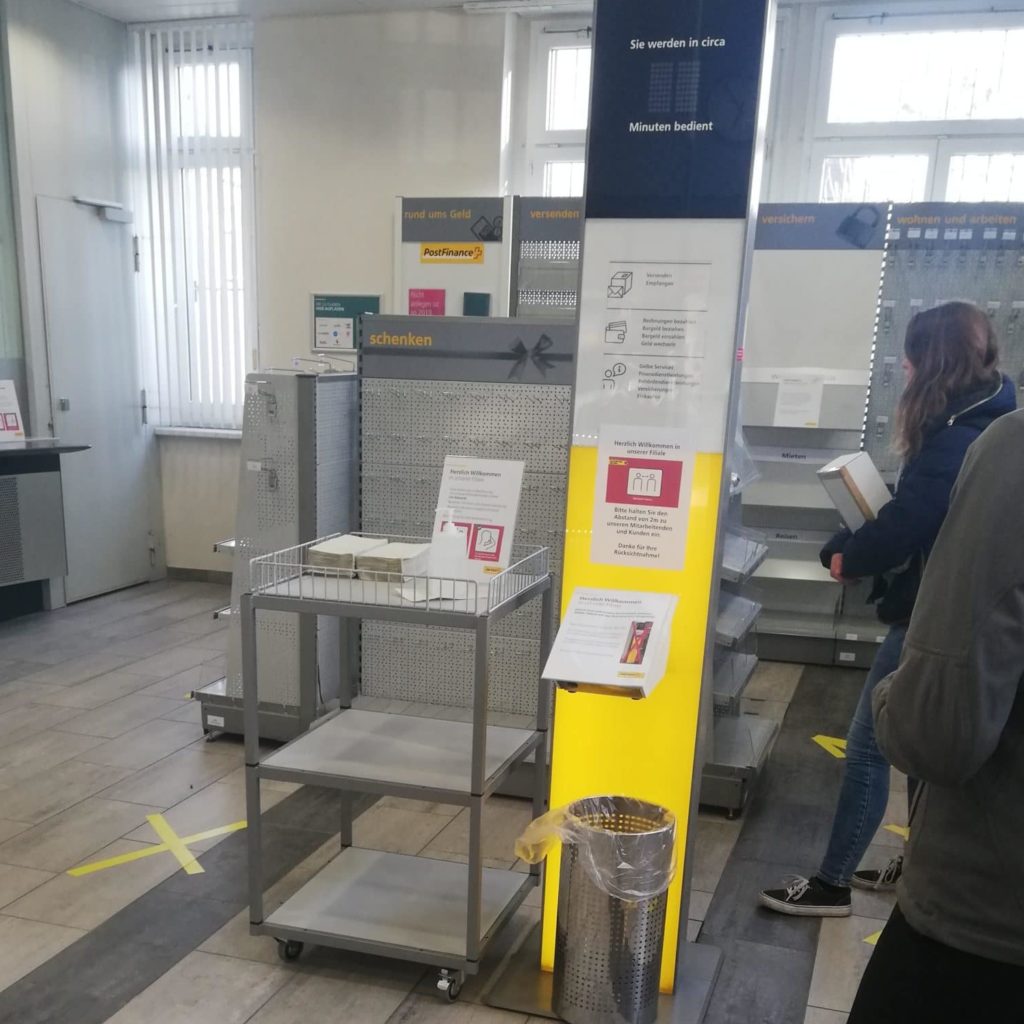 Desinfektionsstation Post, Sprühflache, offener Abfalleimer und lose rumliegende Handtücher, soll man sich so vor Corona Schützen?